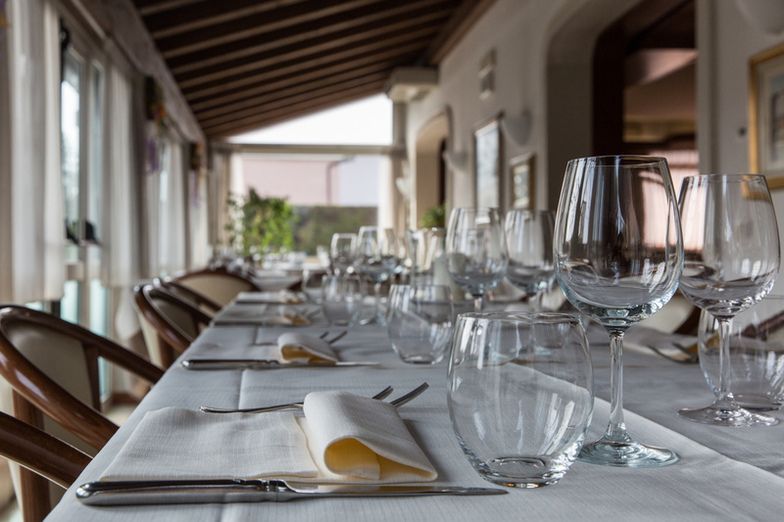 Un lungo tavolo con bicchieri e posate in un ristorante.