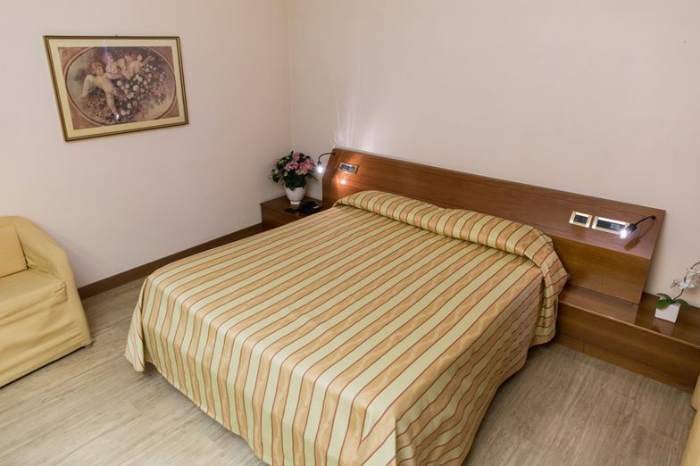 A hotel room with a large bed and a chair