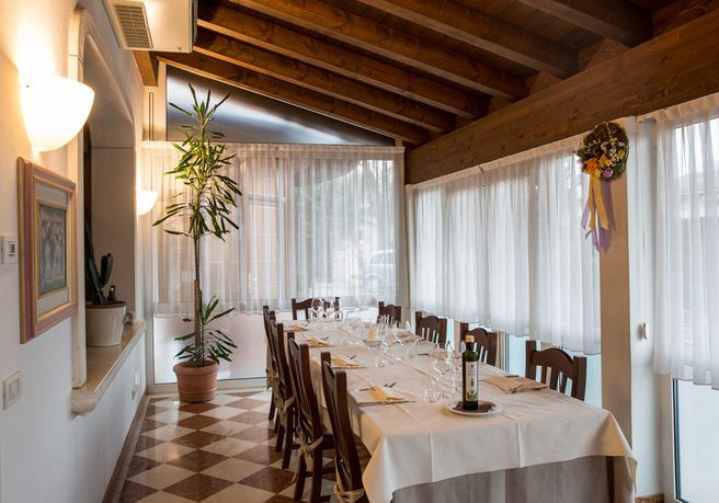 Un lungo tavolo in un ristorante con una bottiglia di vino sopra.