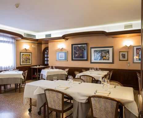A restaurant with tables and chairs and paintings on the wall