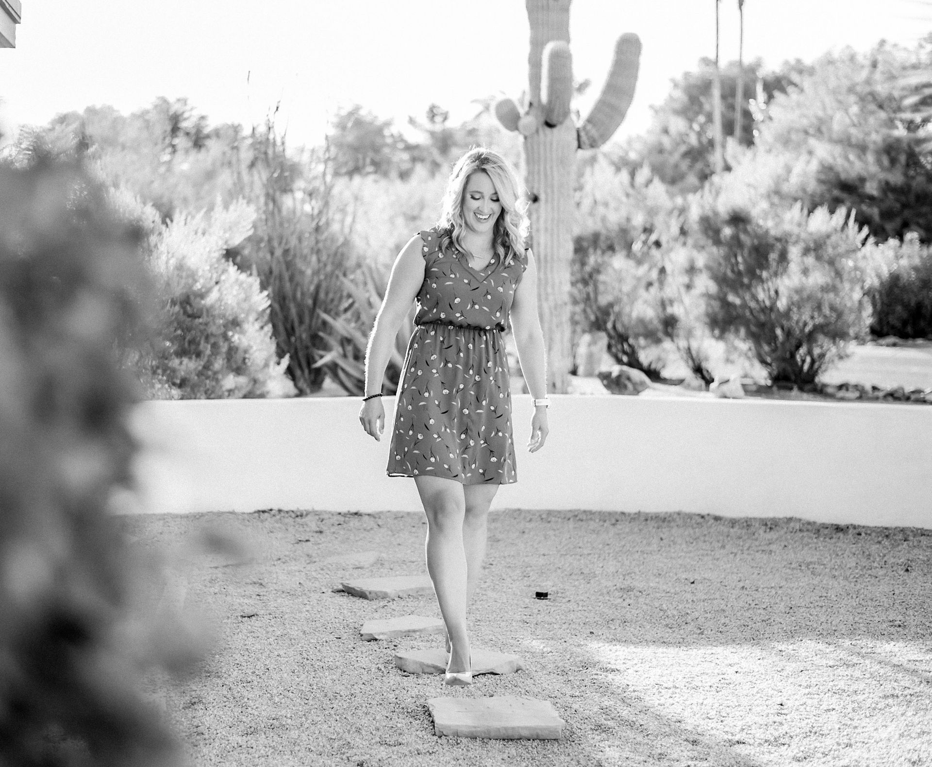 A woman in a dress is walking on a gravel path in a black and white photo.