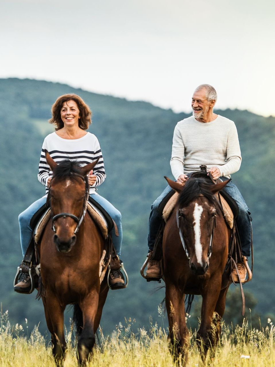 A man and a woman are riding horses in a field.