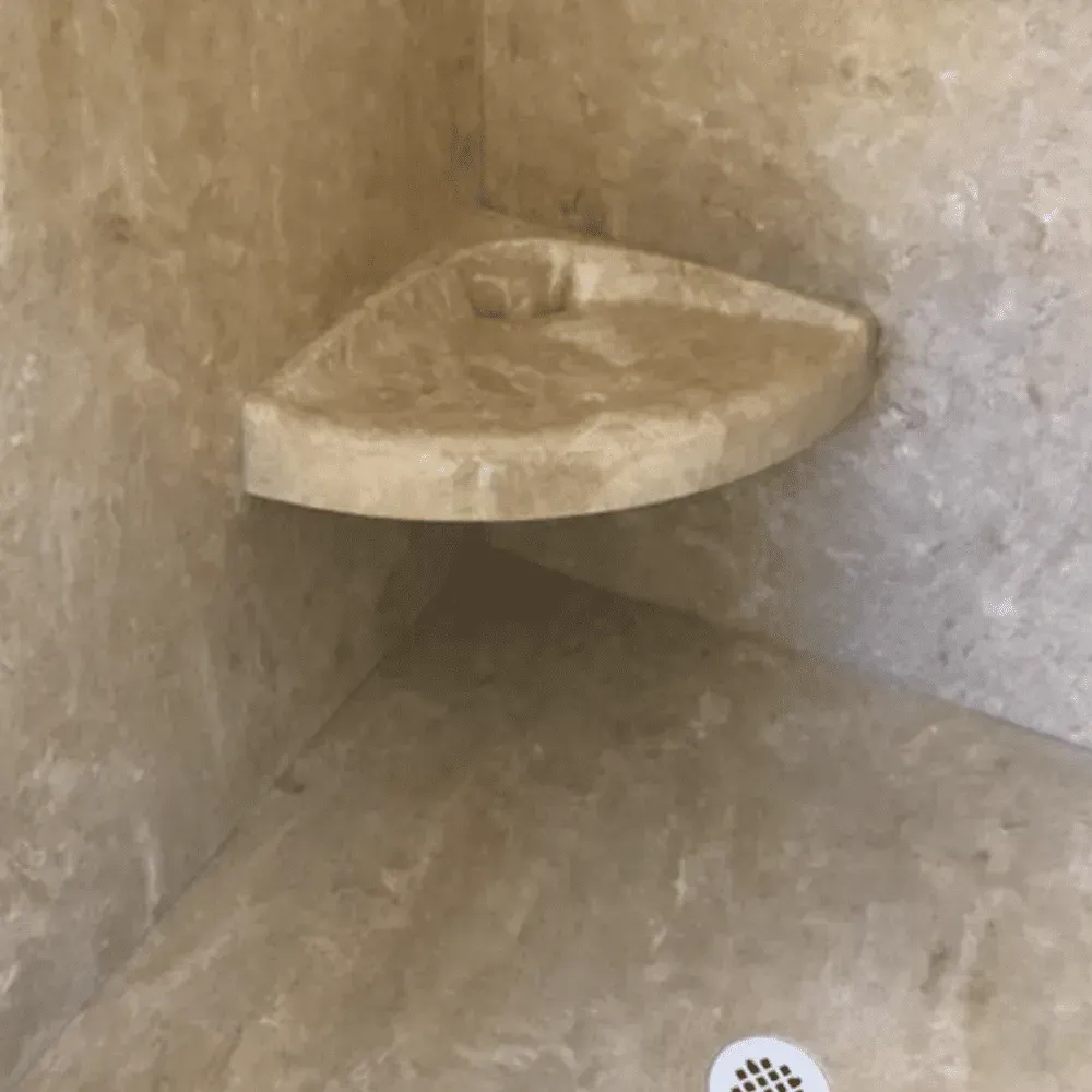 Beige corner shower with built-in triangular shelf by Syn-Mar