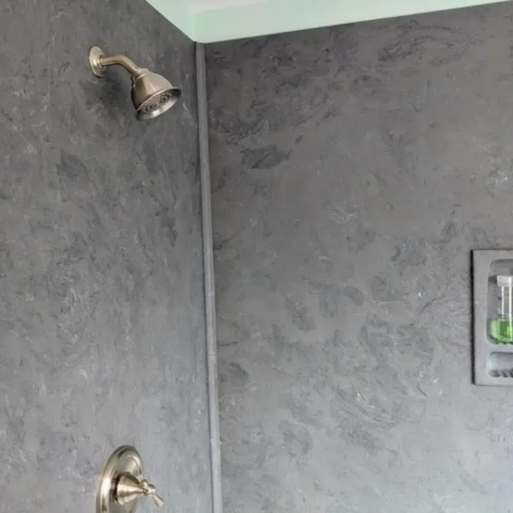 Shower with gray marbled walls, silver fixtures, and a recessed soap shelf by Syn-Mar