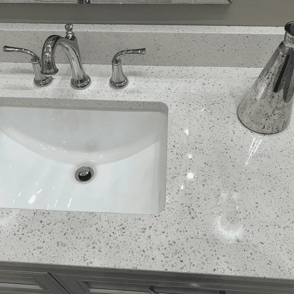 White bathroom sink with chrome faucet on speckled countertop by Syn-Mar