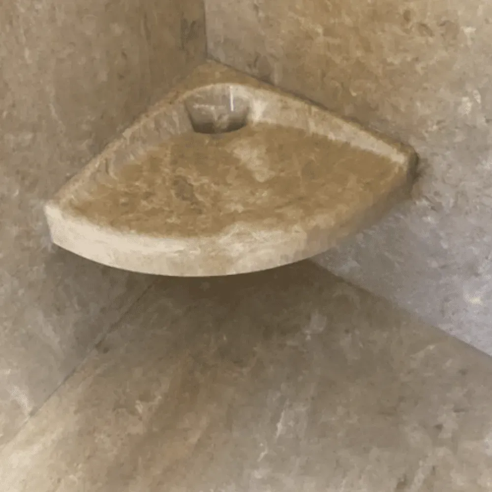 Corner shower shelf made of tan stone by Syn-Mar