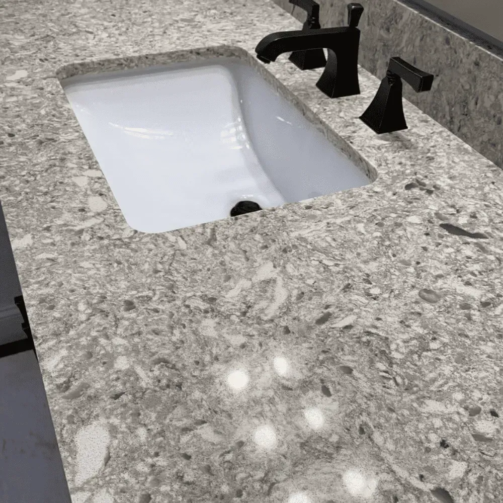 White bathroom sink with black faucet on speckled countertop by Syn-Mar