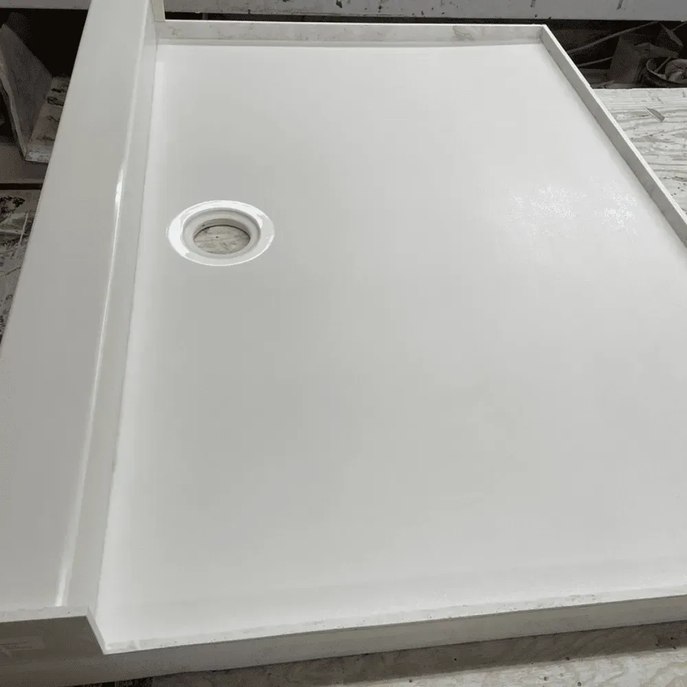 White rectangular shower base with drain, raised edges, and glossy surface by Syn-Mar