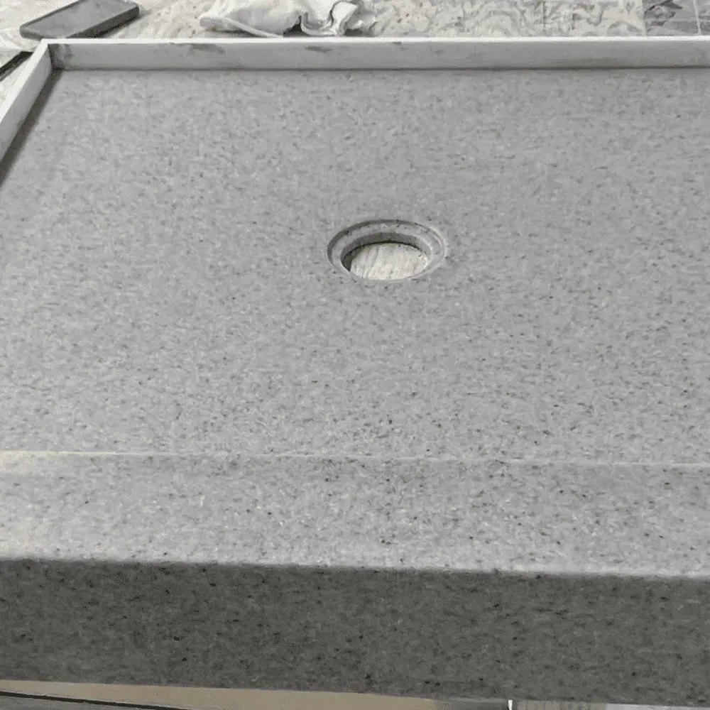 Gray speckled shower base with a drain hole by Syn-Mar