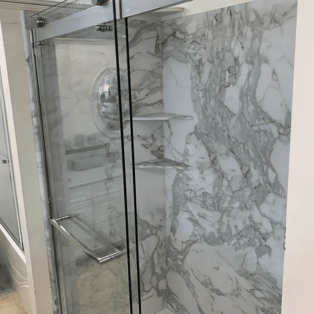 Glass-enclosed shower with marble walls, glass shelves, and chrome fixtures by Syn-Mar