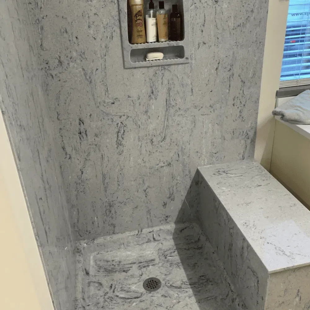 Gray and white marble-look shower with built-in bench and soap niche by Syn-Mar