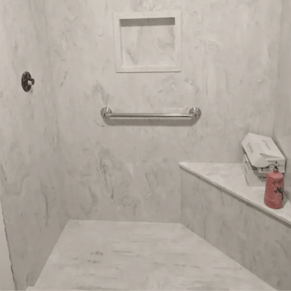 Shower stall with marble-like walls, a built-in bench, towel bar, and soap dispenser by Syn-Mar