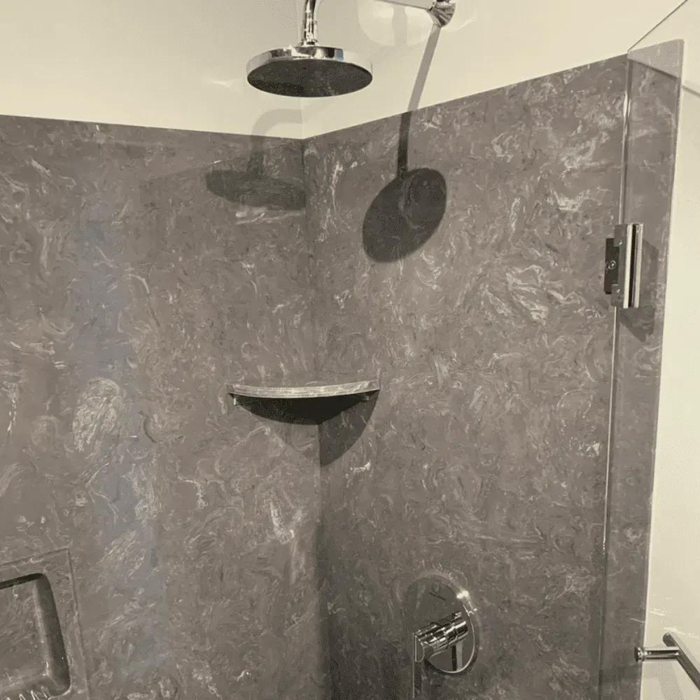 Shower stall with dark, marbled walls. Silver showerhead and controls by Syn-Mar