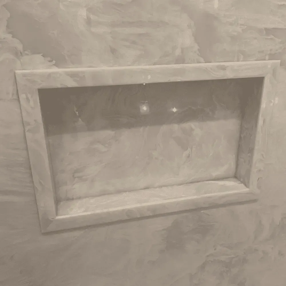Recessed, rectangular shower shelf built into a textured, white wall by Syn-Mar