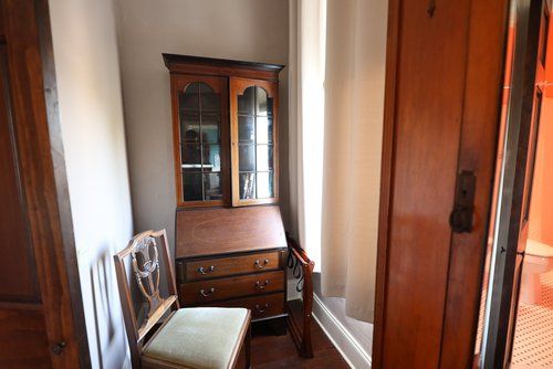 A corner of a room with a chair and a dresser.
