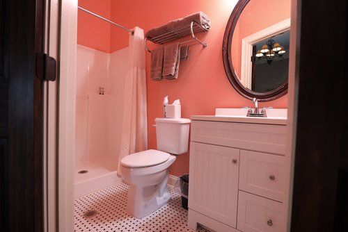 A bathroom with a toilet , sink , shower and mirror.