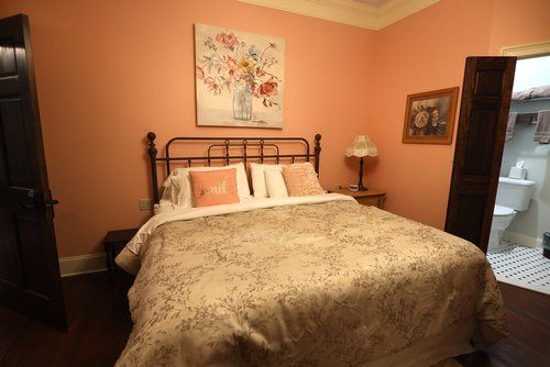 A bedroom with a bed , nightstand , lamp and painting on the wall.