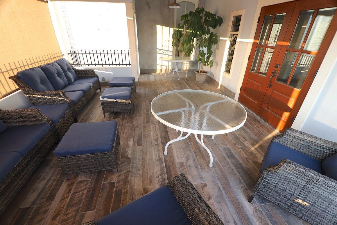 A patio with wicker furniture and a glass table