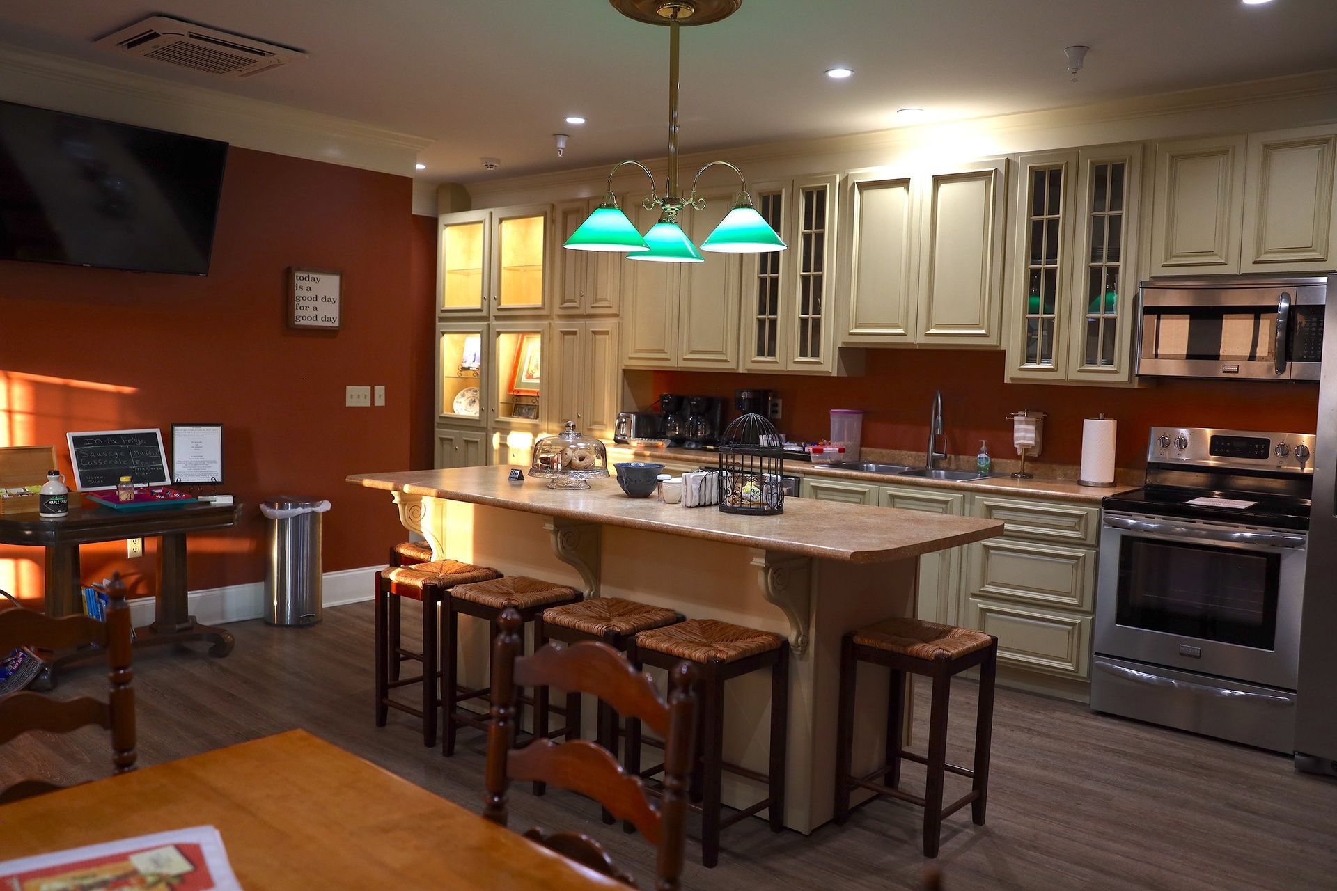 A kitchen with white cabinets , stainless steel appliances , a large island , a table and chairs.