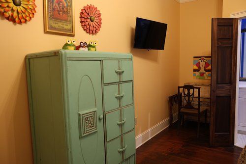 A room with a dresser and a flat screen tv on the wall.