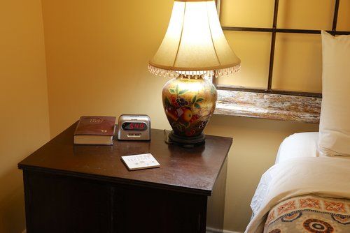 A lamp is sitting on a nightstand next to a bed.