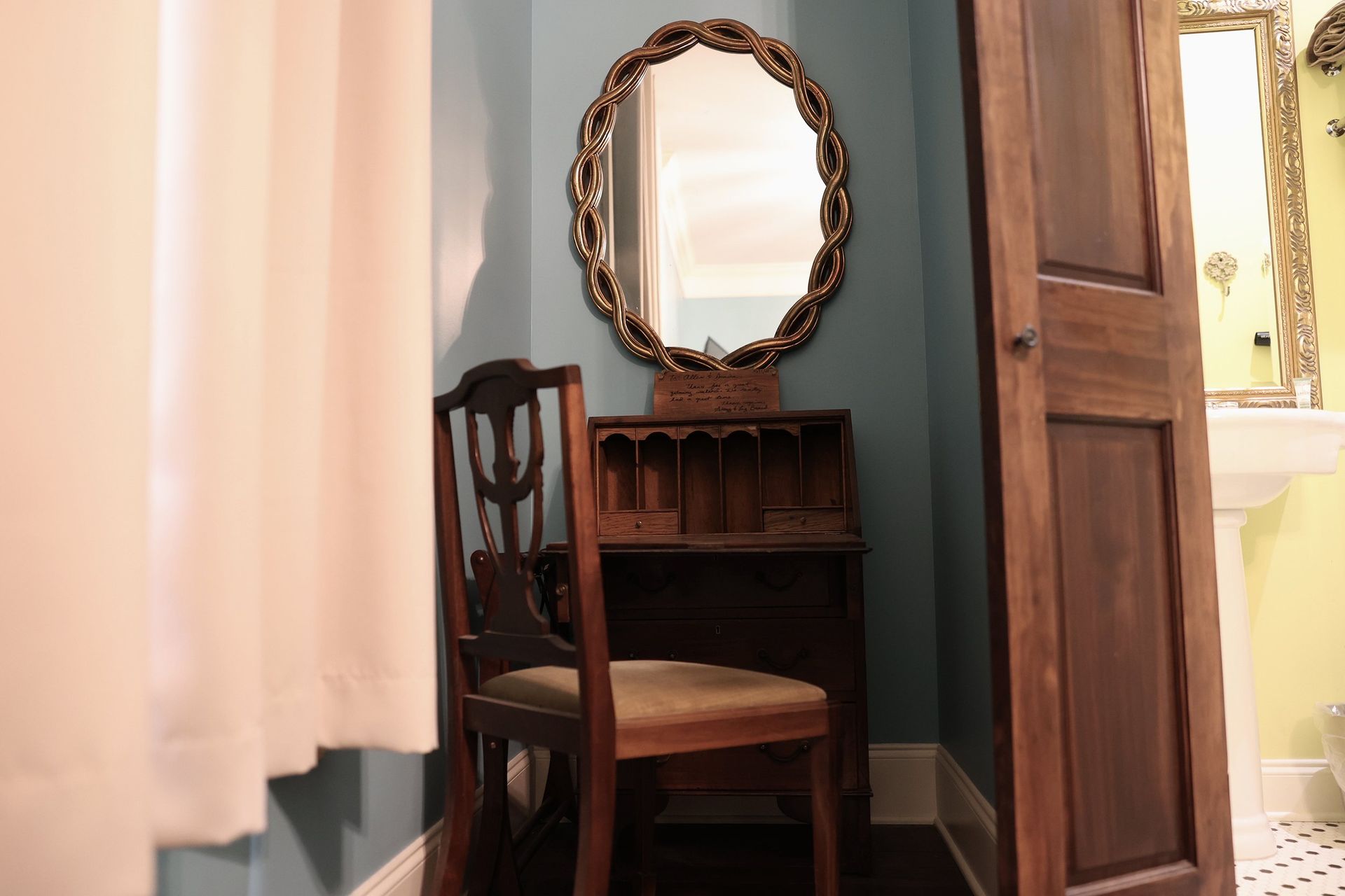 A vanity with a chair and a mirror in a bathroom.