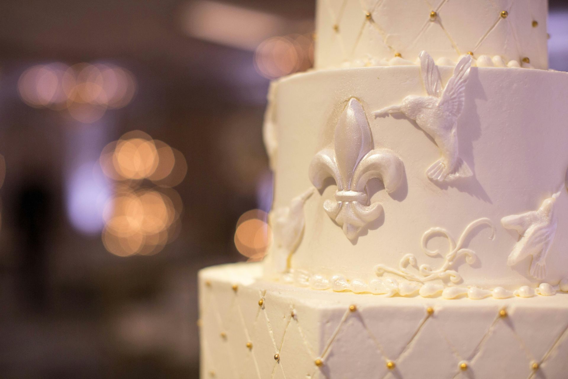 A close up of a wedding cake with a fleur de lis on it.