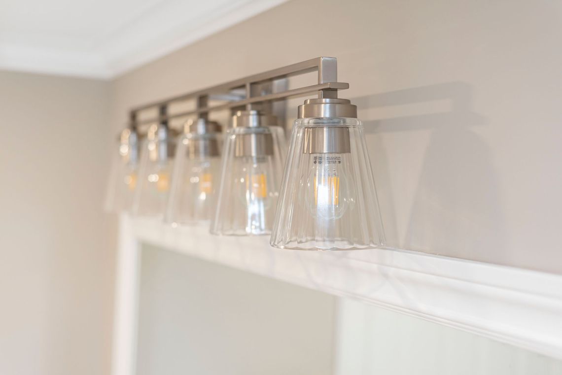 a bathroom vanity light with clear glass shades is hanging on a wall .