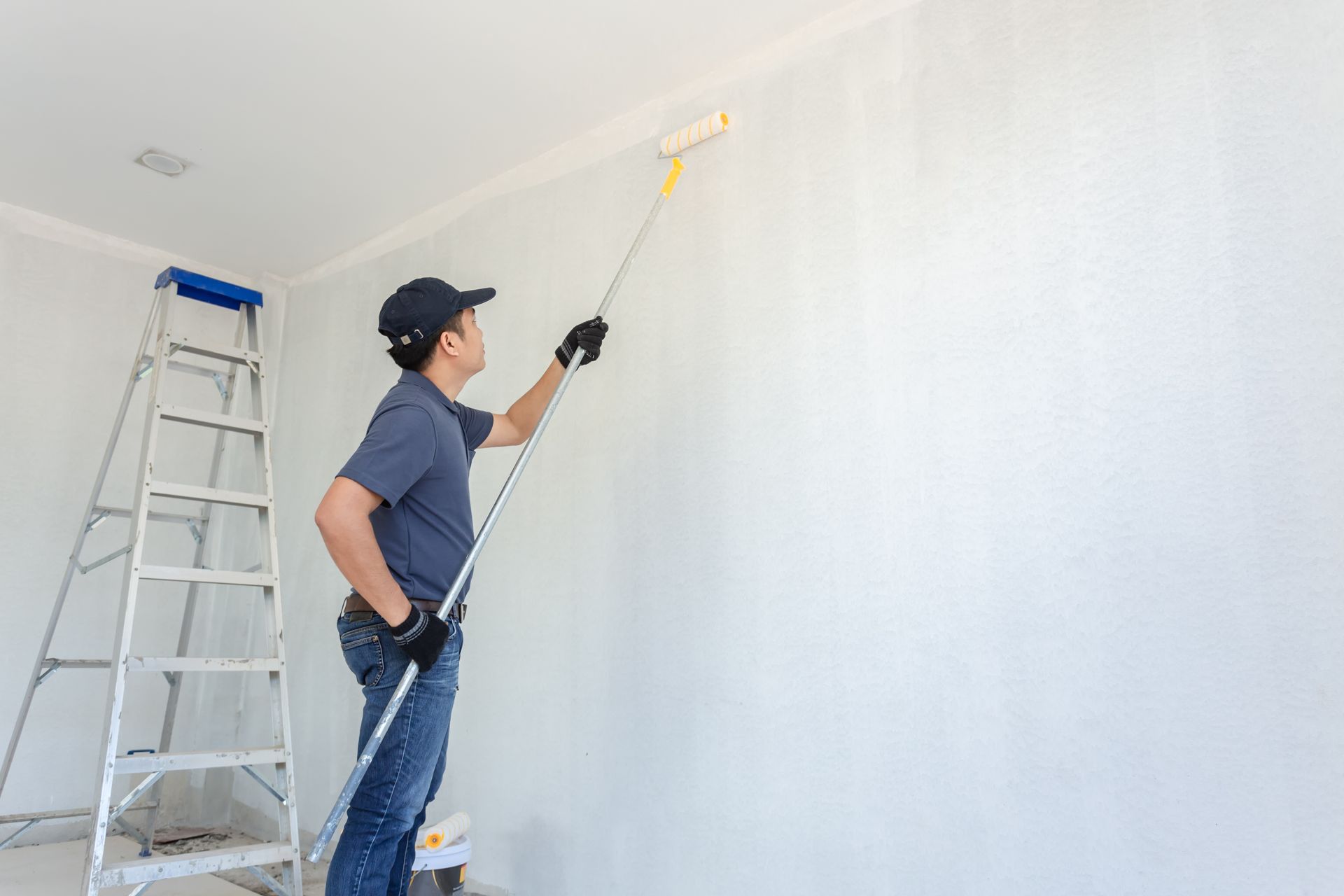 a man is painting a wall with a paint roller .