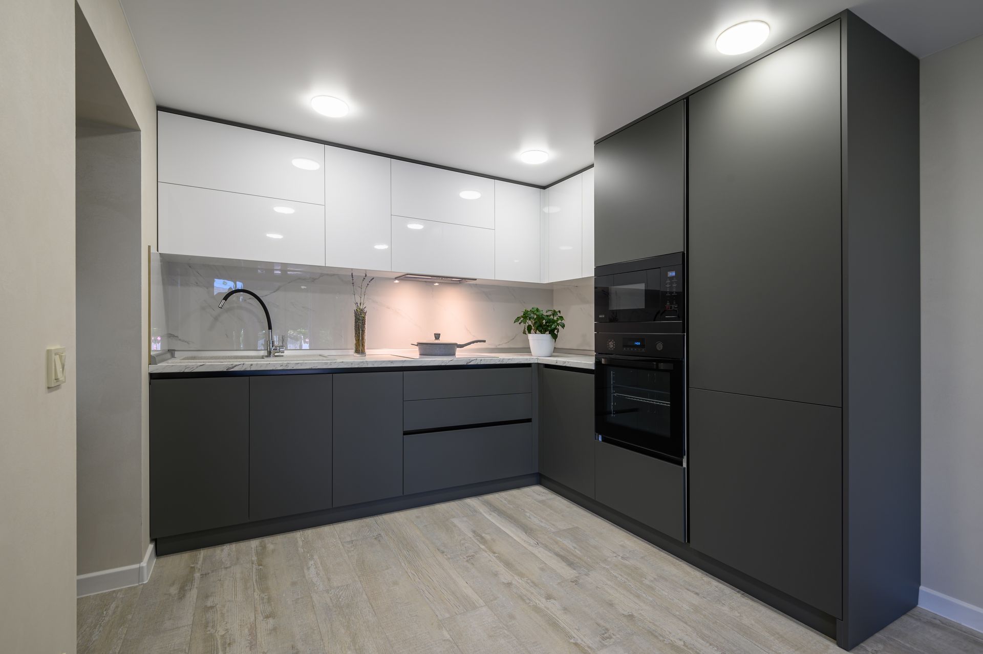 a kitchen with gray and white cabinets and a wooden floor .