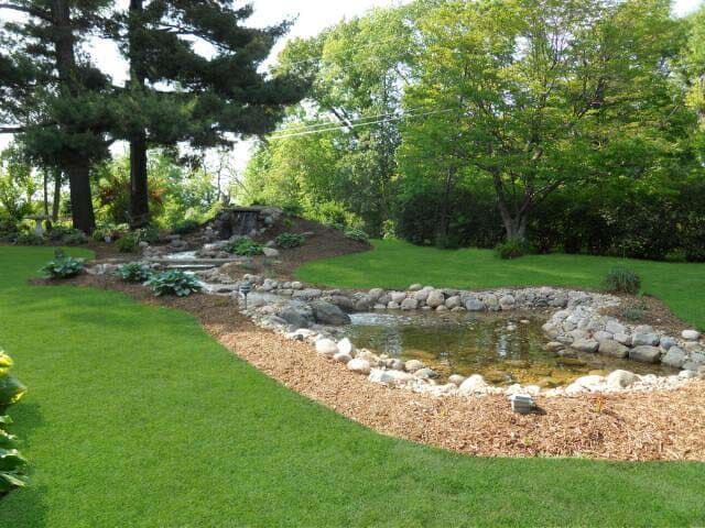 A Pond in the Middle of a Lush Green Field - Orion, IL - C & J Landscaping