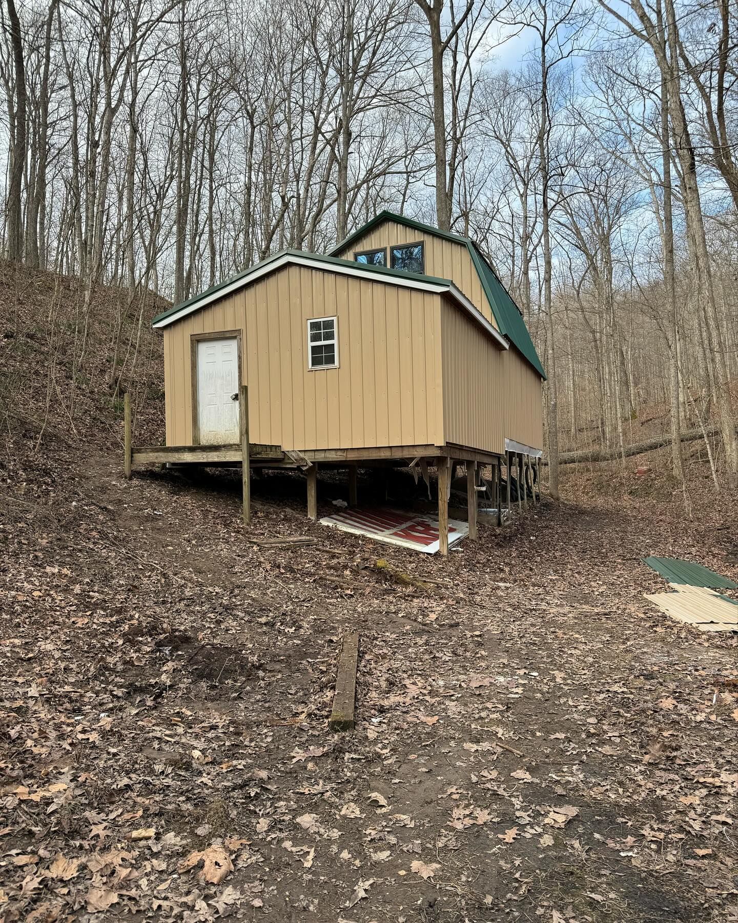 A small house is sitting on top of a hill in the woods.