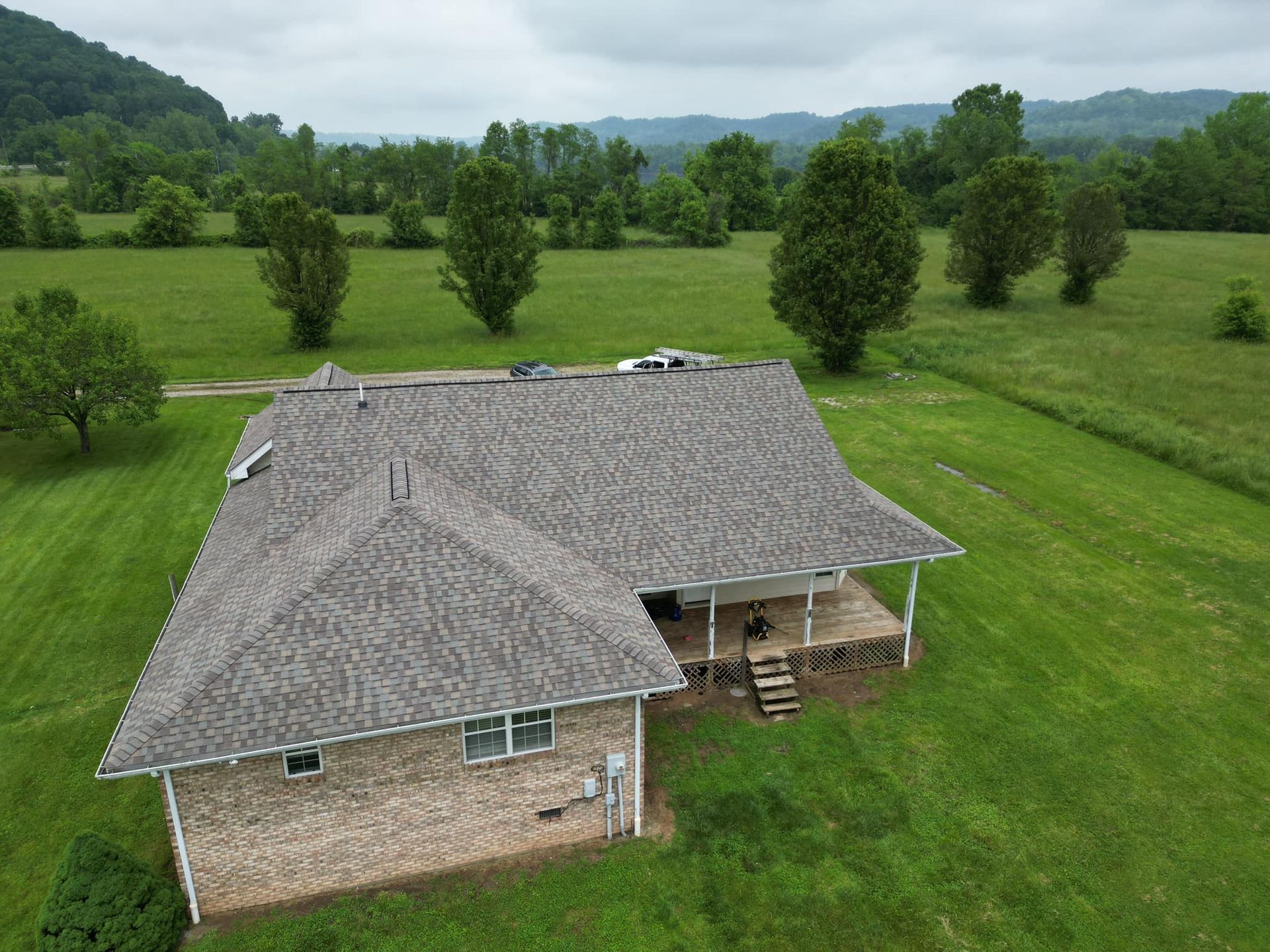 An aerial view of a house in the middle of a grassy field.