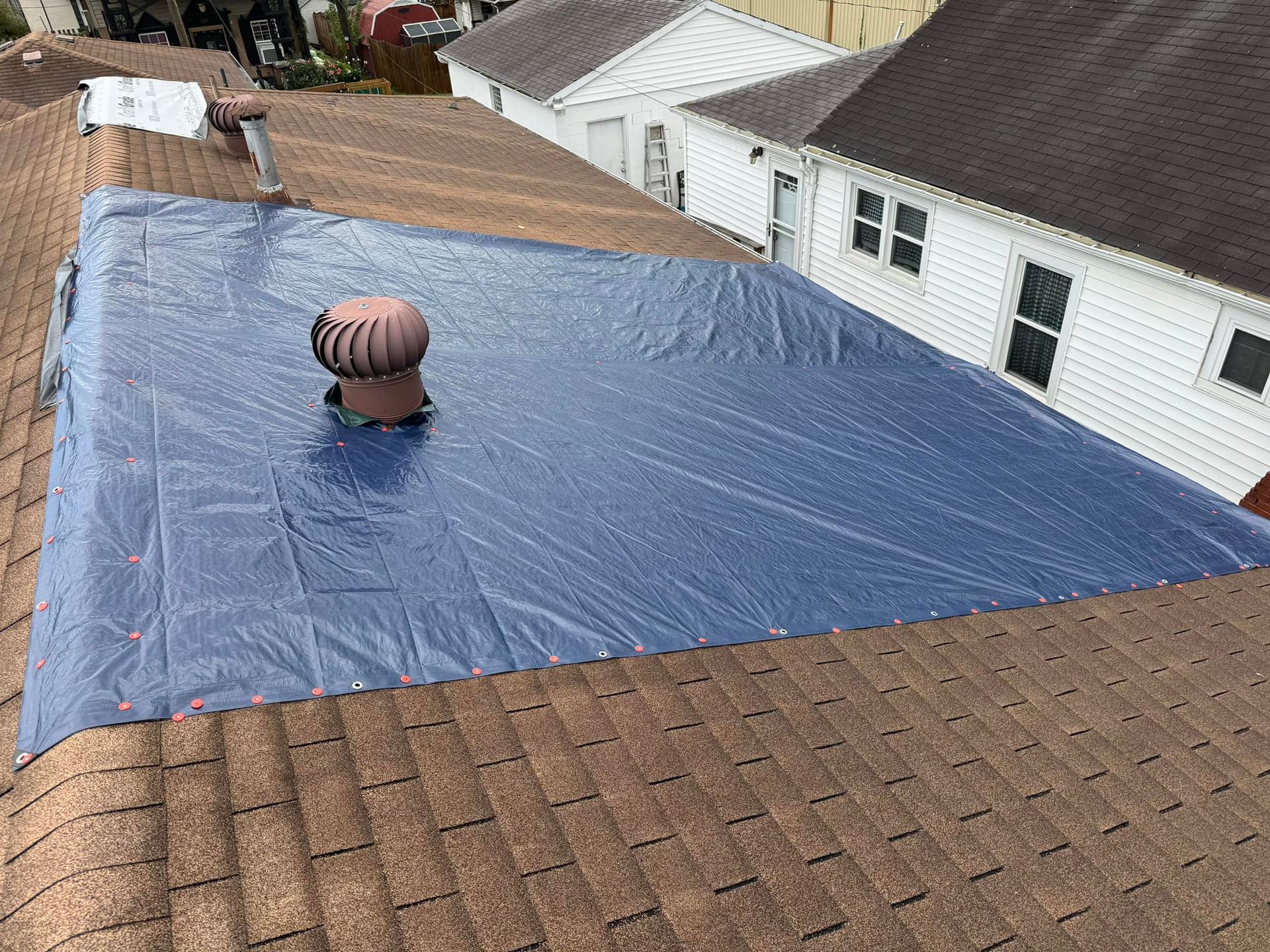 A blue tarp is covering the roof of a house.