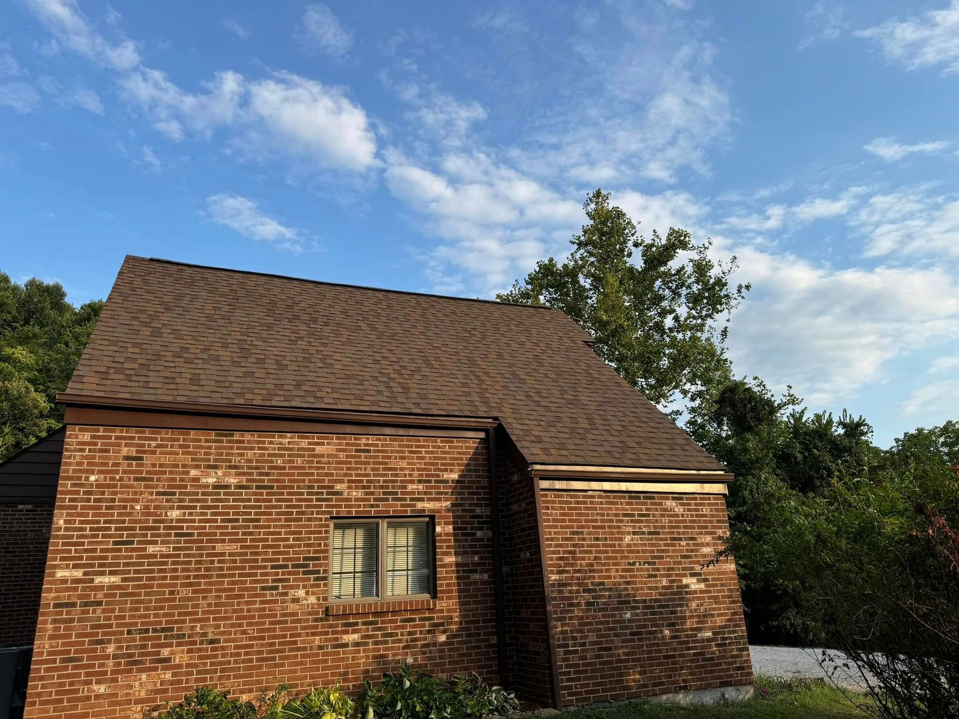 A brick house with a brown roof and a window.