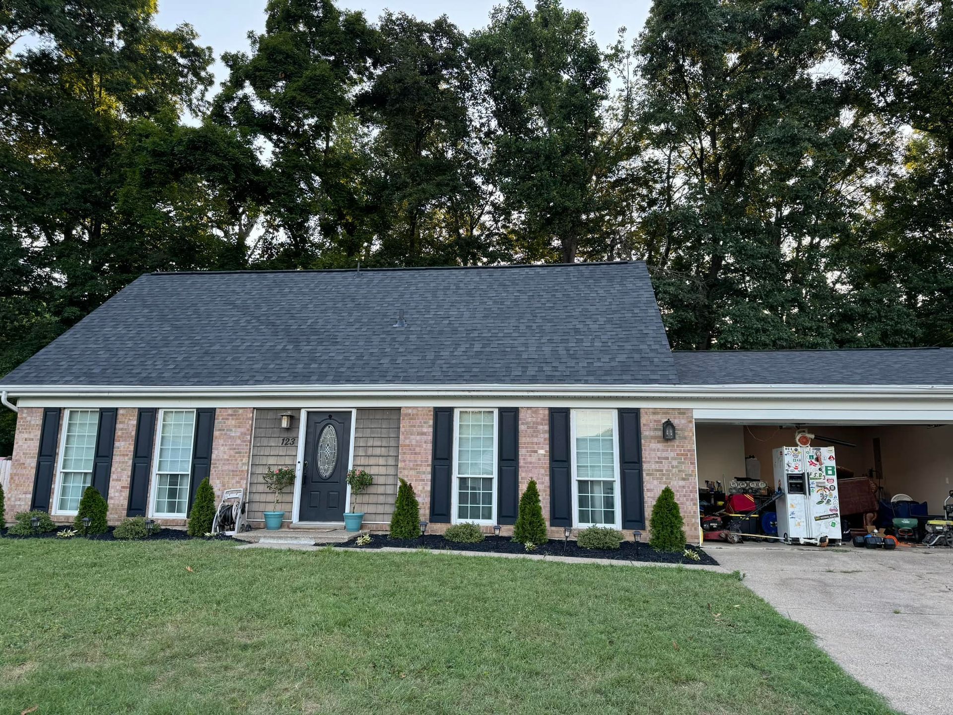 A brick house with a blue roof and black shutters