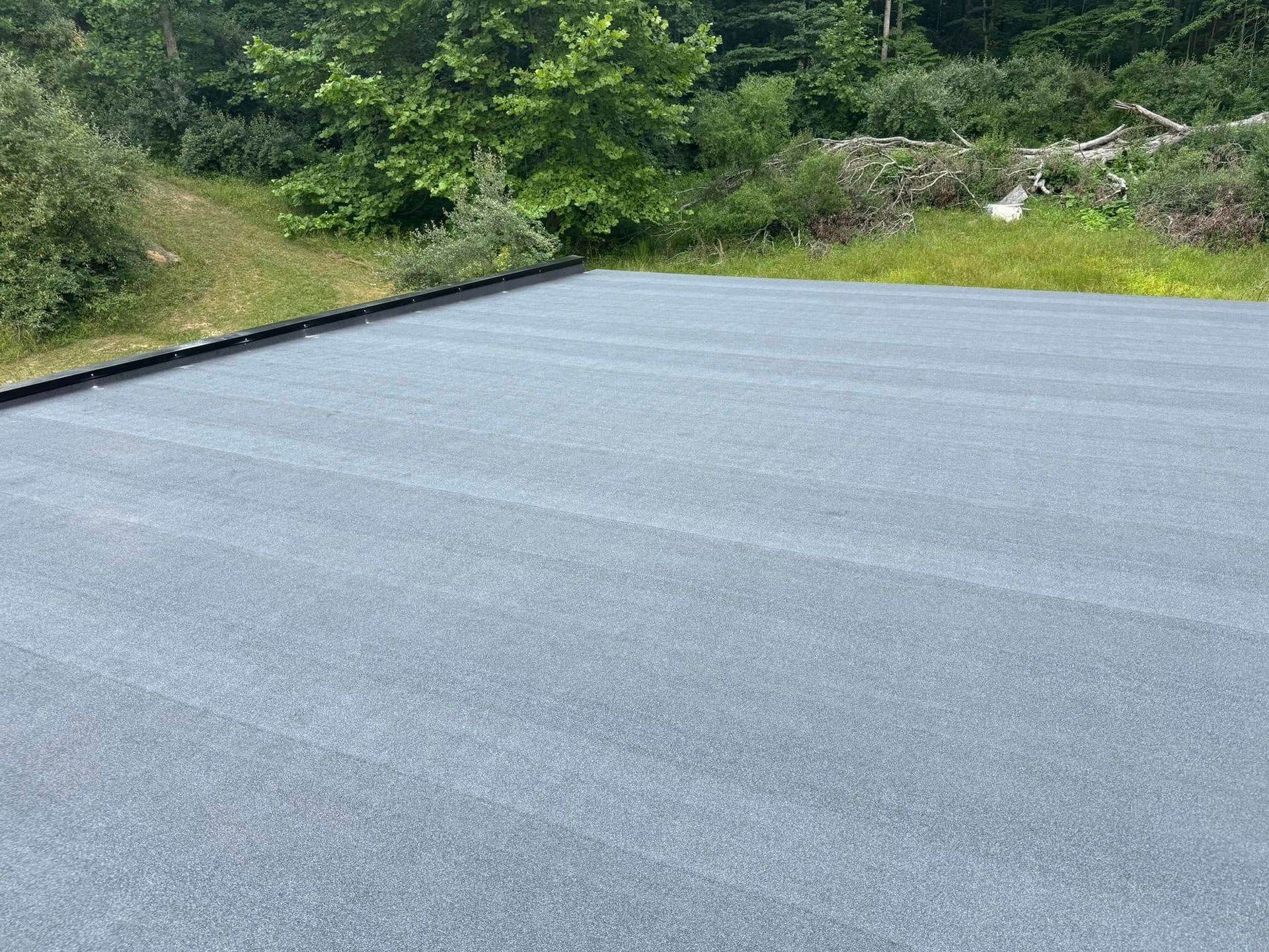 A large empty parking lot with trees in the background.