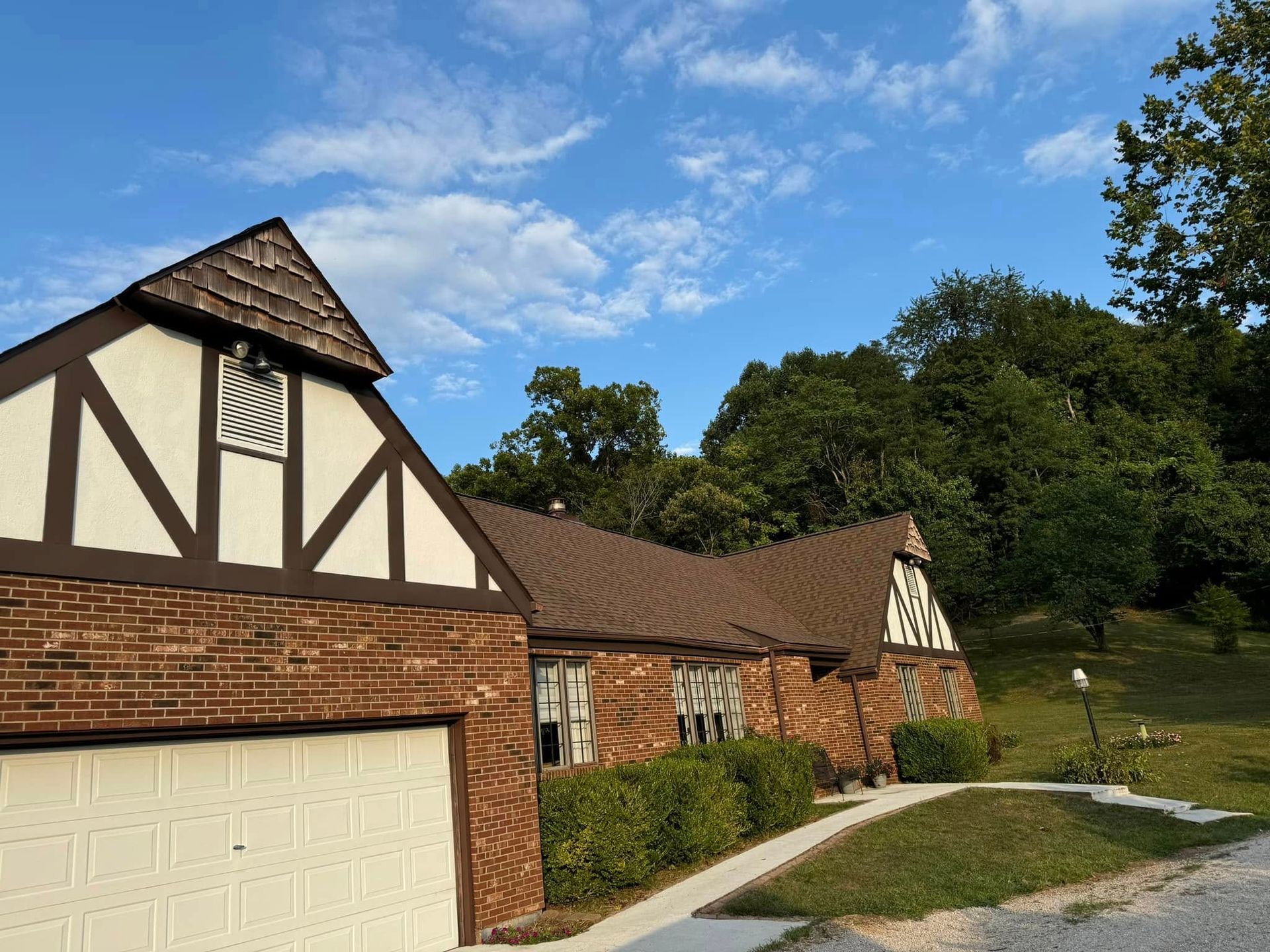 A brick house with a brown roof and a white garage door