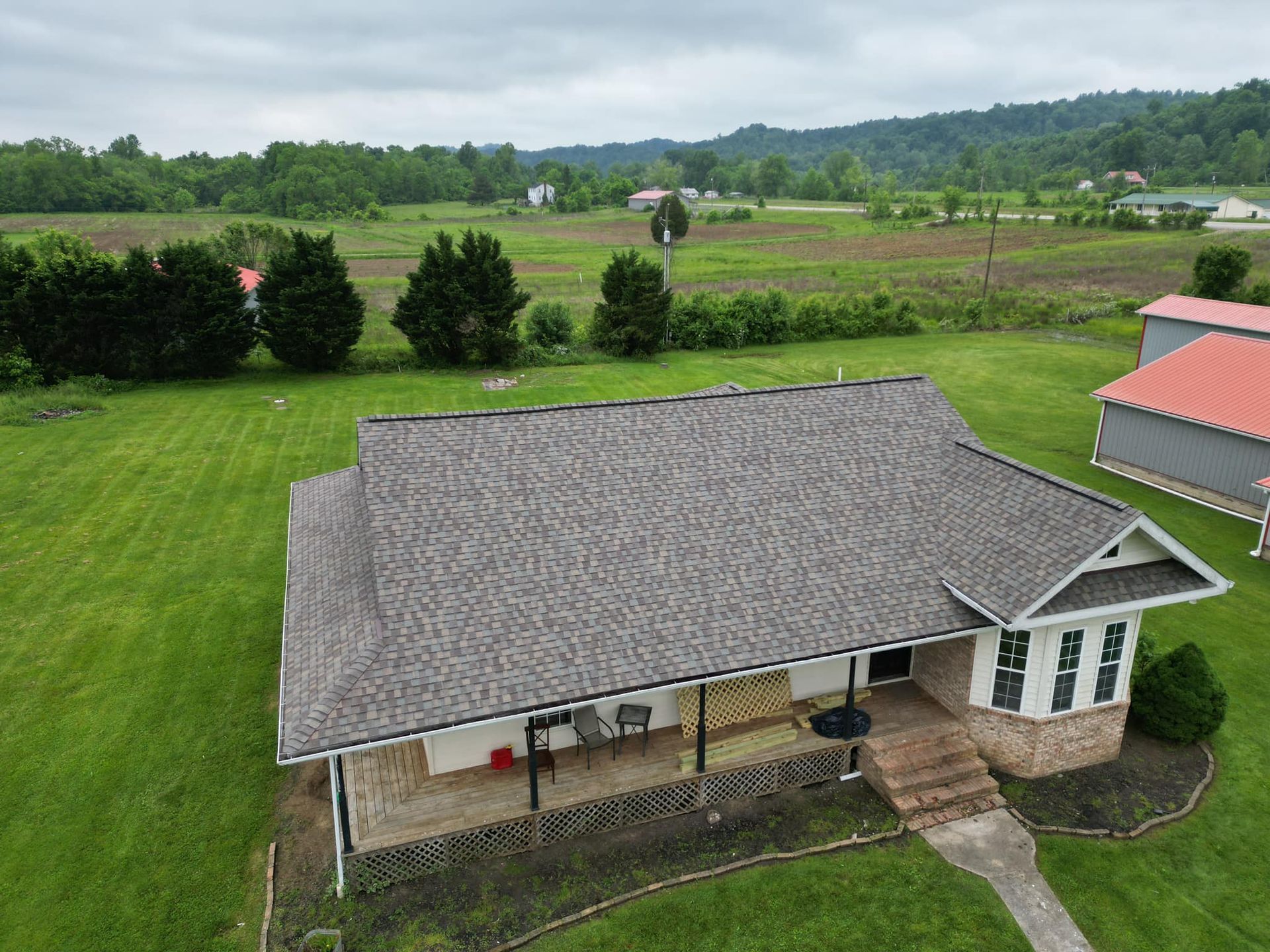 An aerial view of a house in the middle of a grassy field.