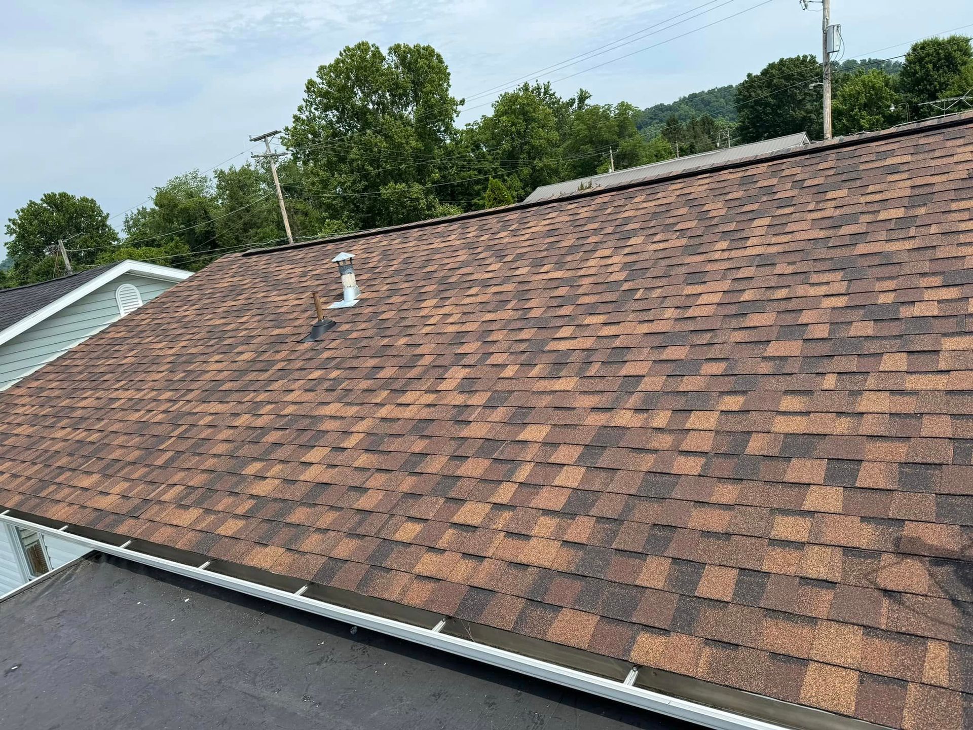 The roof of a house with a brown shingle roof.