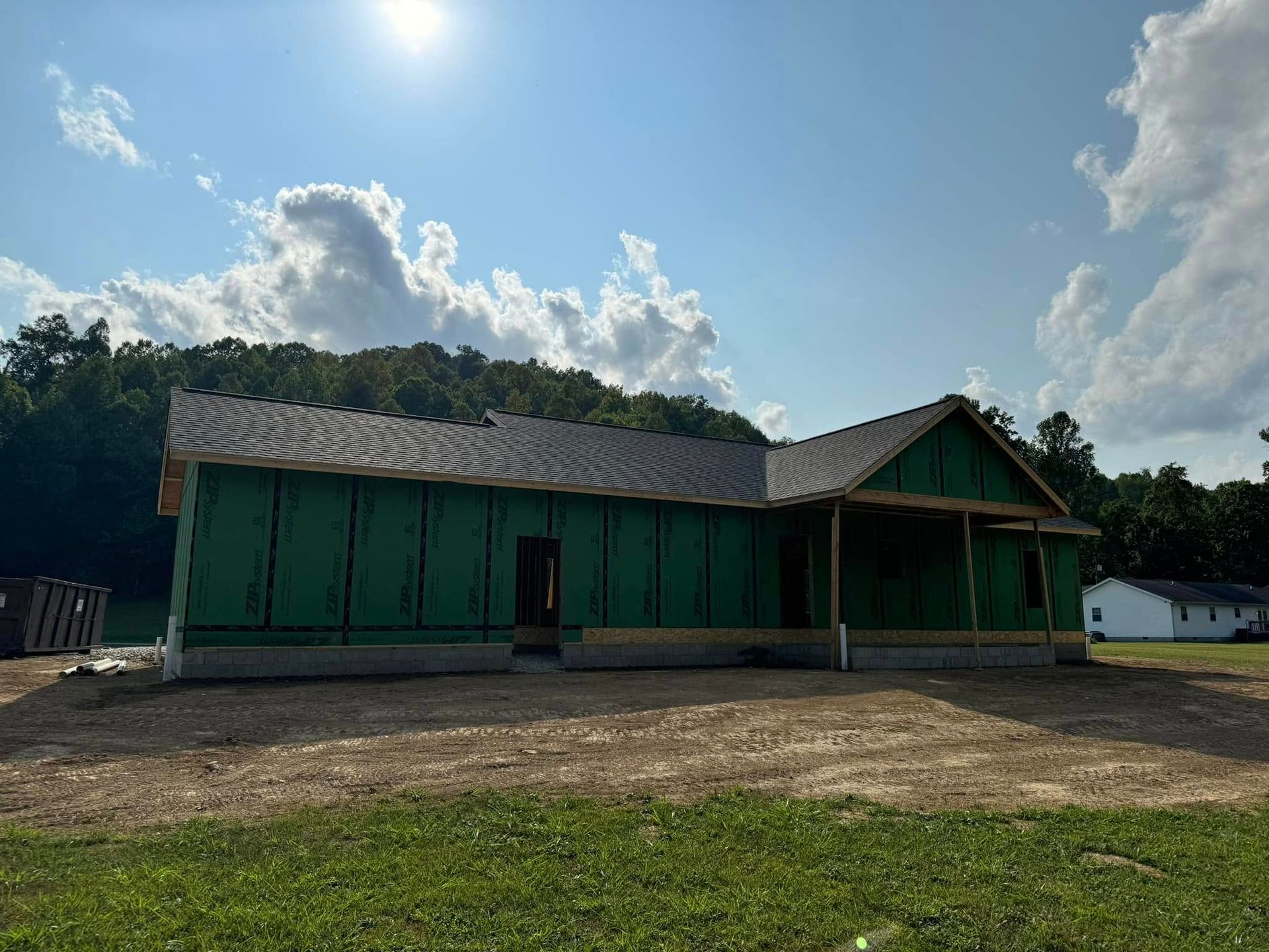 A large green house is being built in a field.