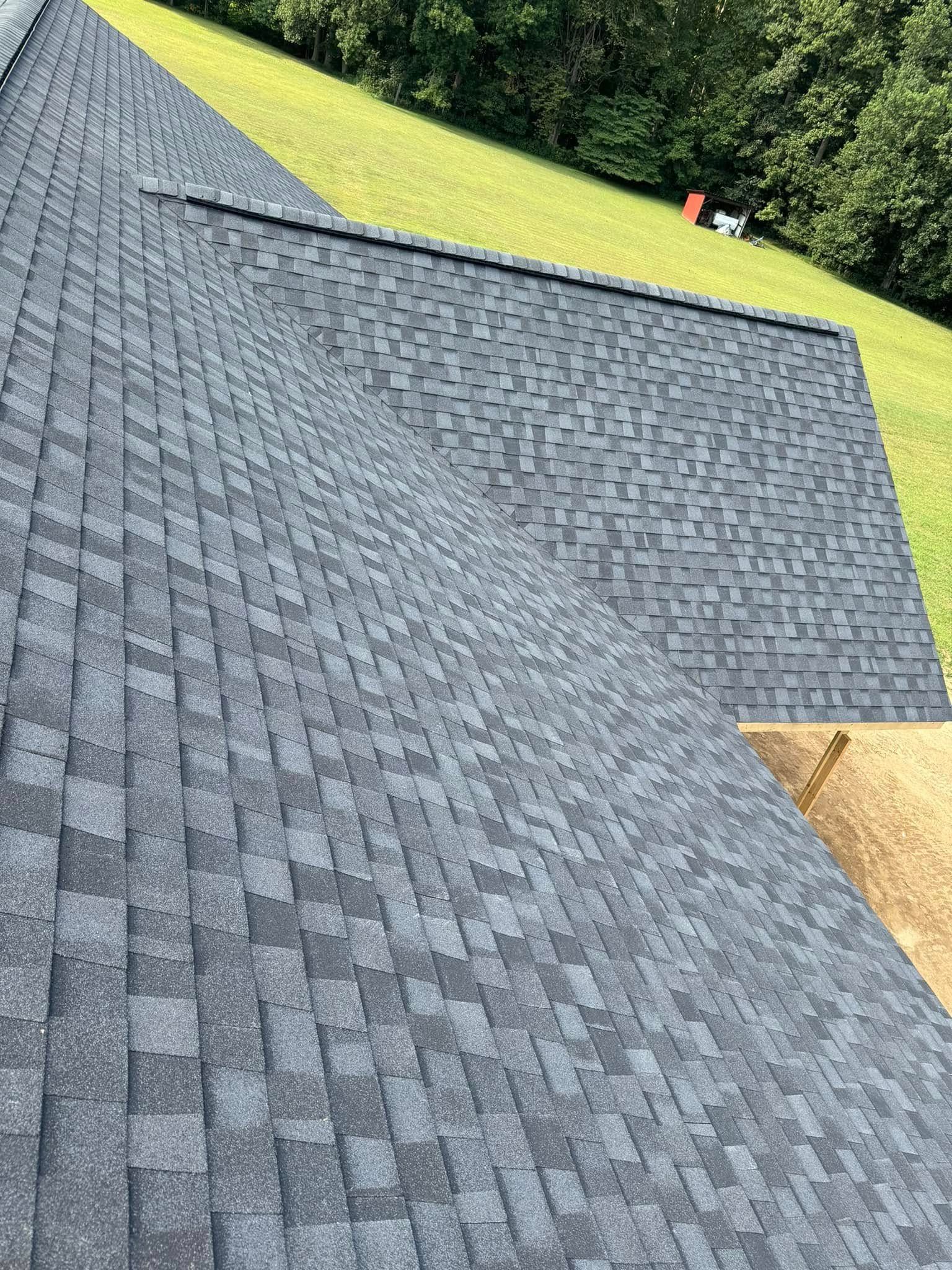 A roof with a lot of shingles is sitting on top of a grassy hill.