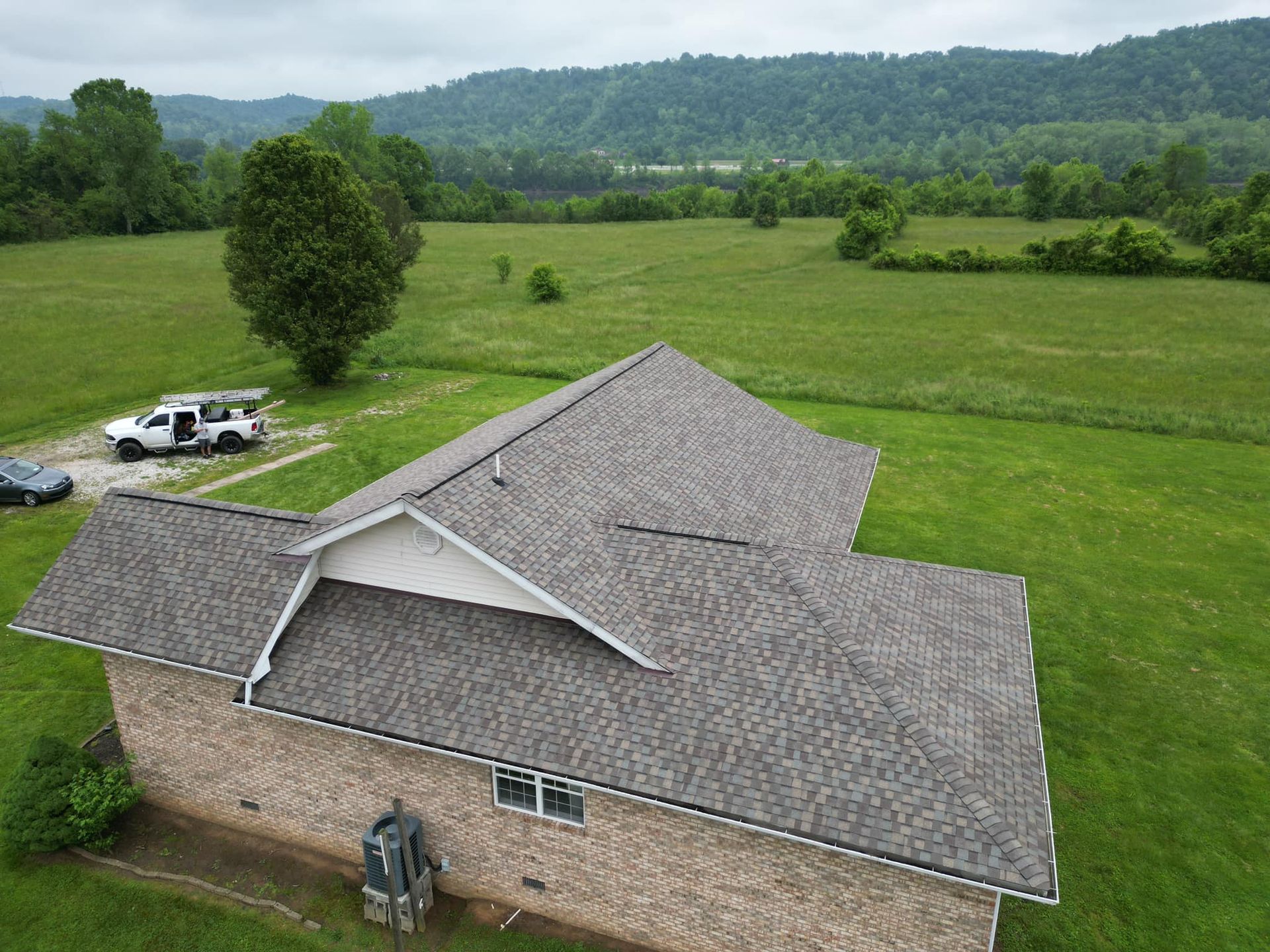 An aerial view of a house with a roof in a field.