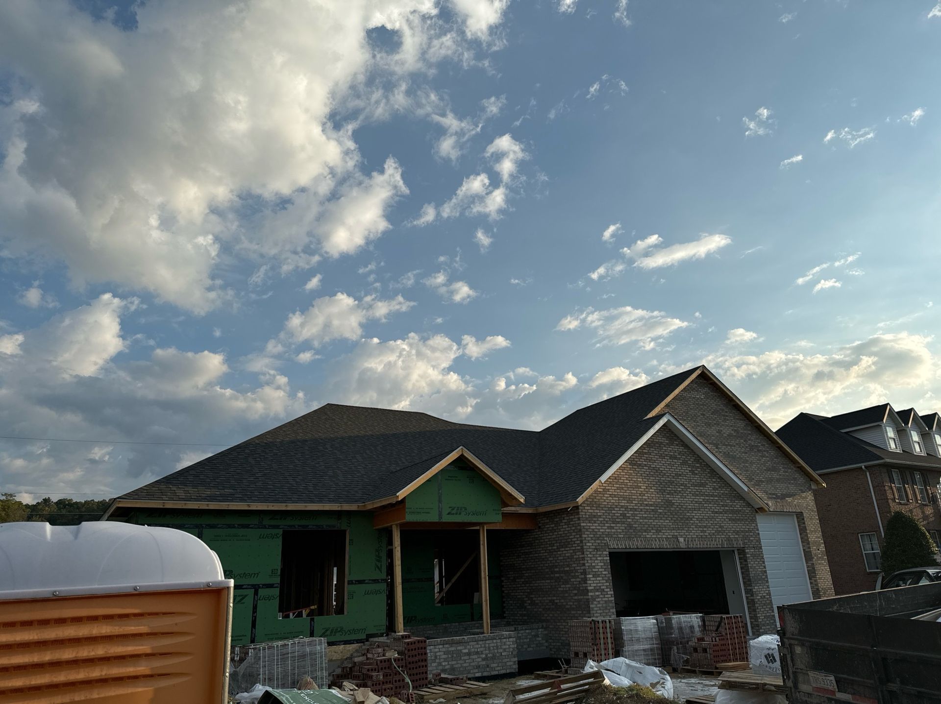 A house under construction with a blue sky and clouds in the background