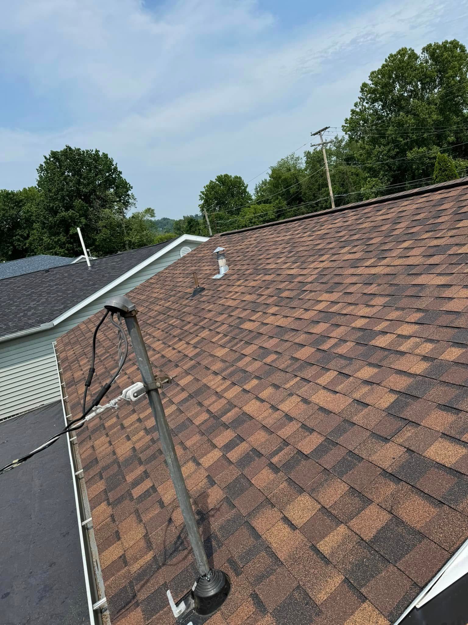 A close up of a roof of a house with trees in the background.