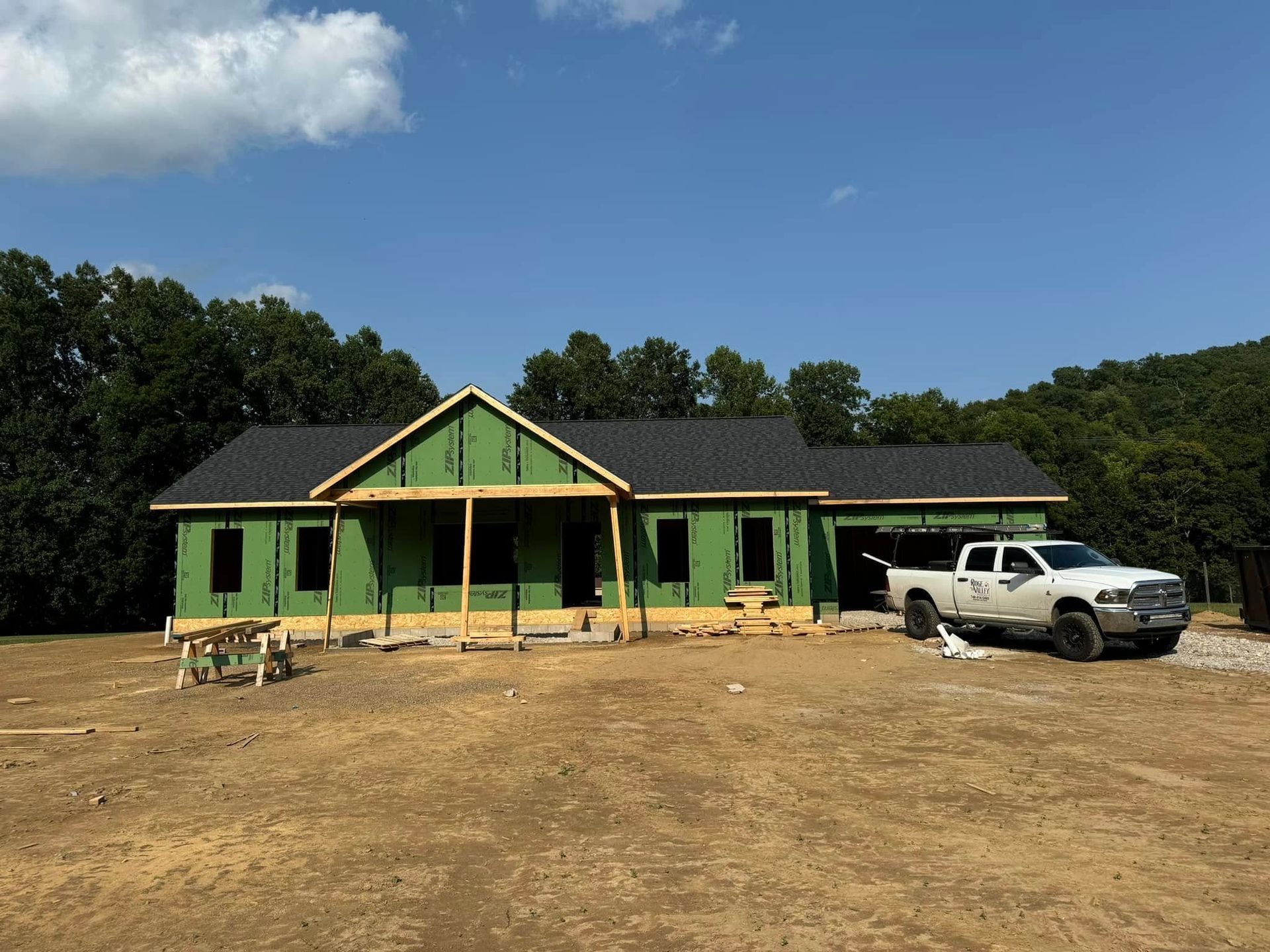A white truck is parked in front of a house under construction.