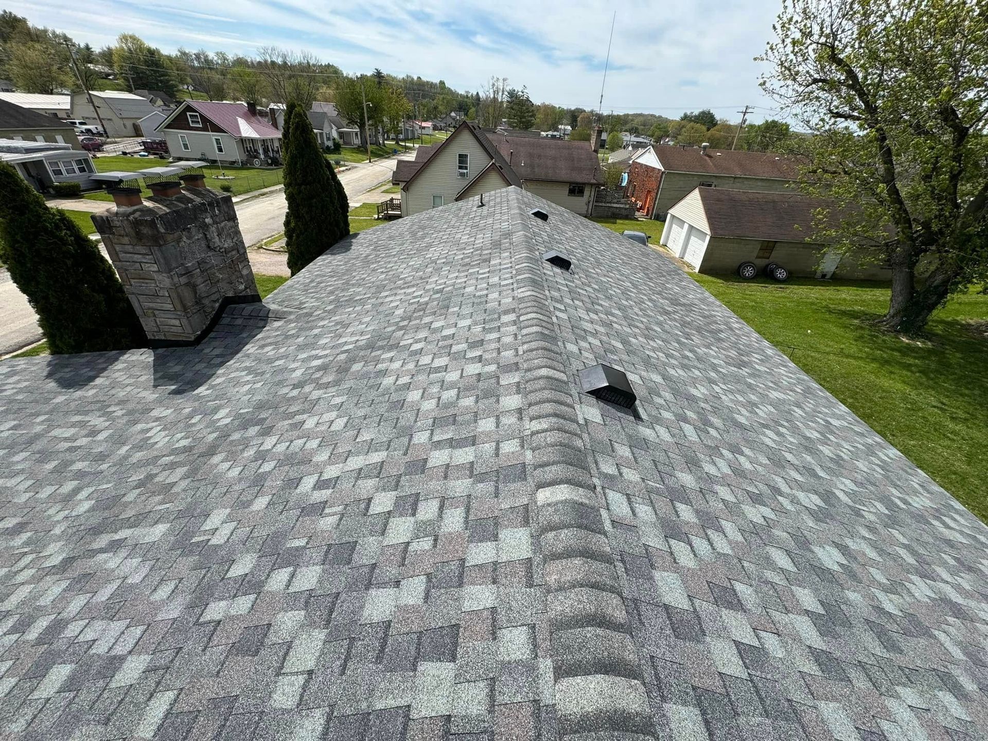 An aerial view of a roof with a chimney on it in a small town.