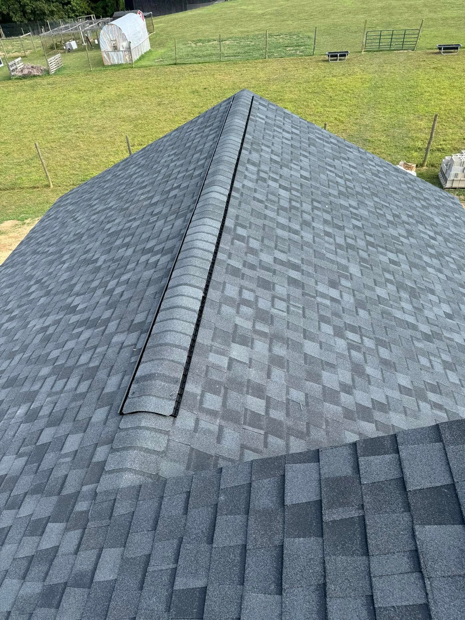 A close up of a roof with shingles on it in a field.