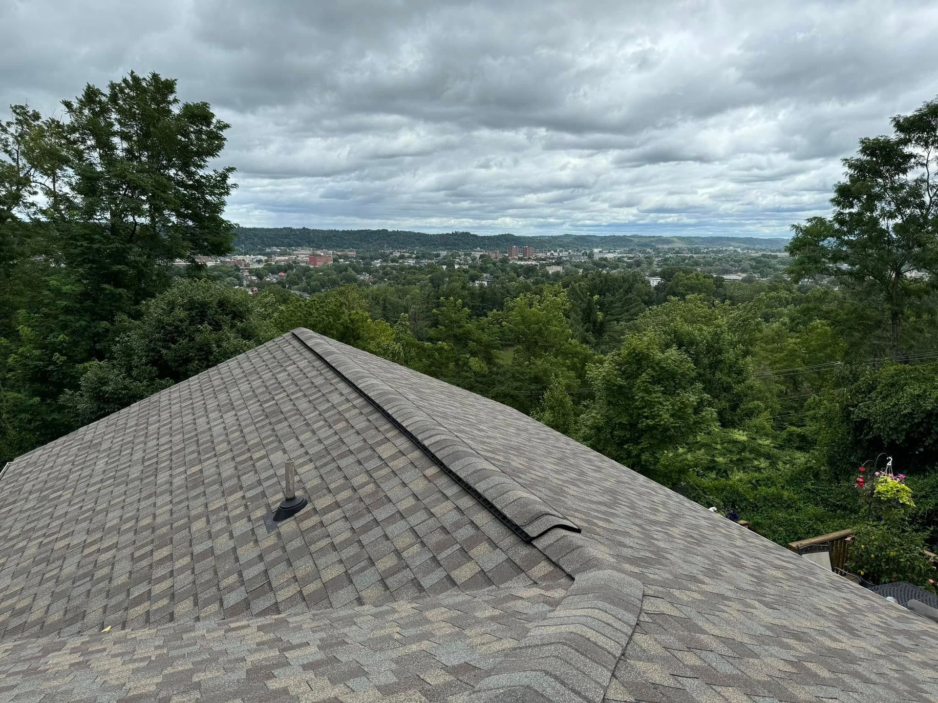 A roof with a view of a city and trees in the background.