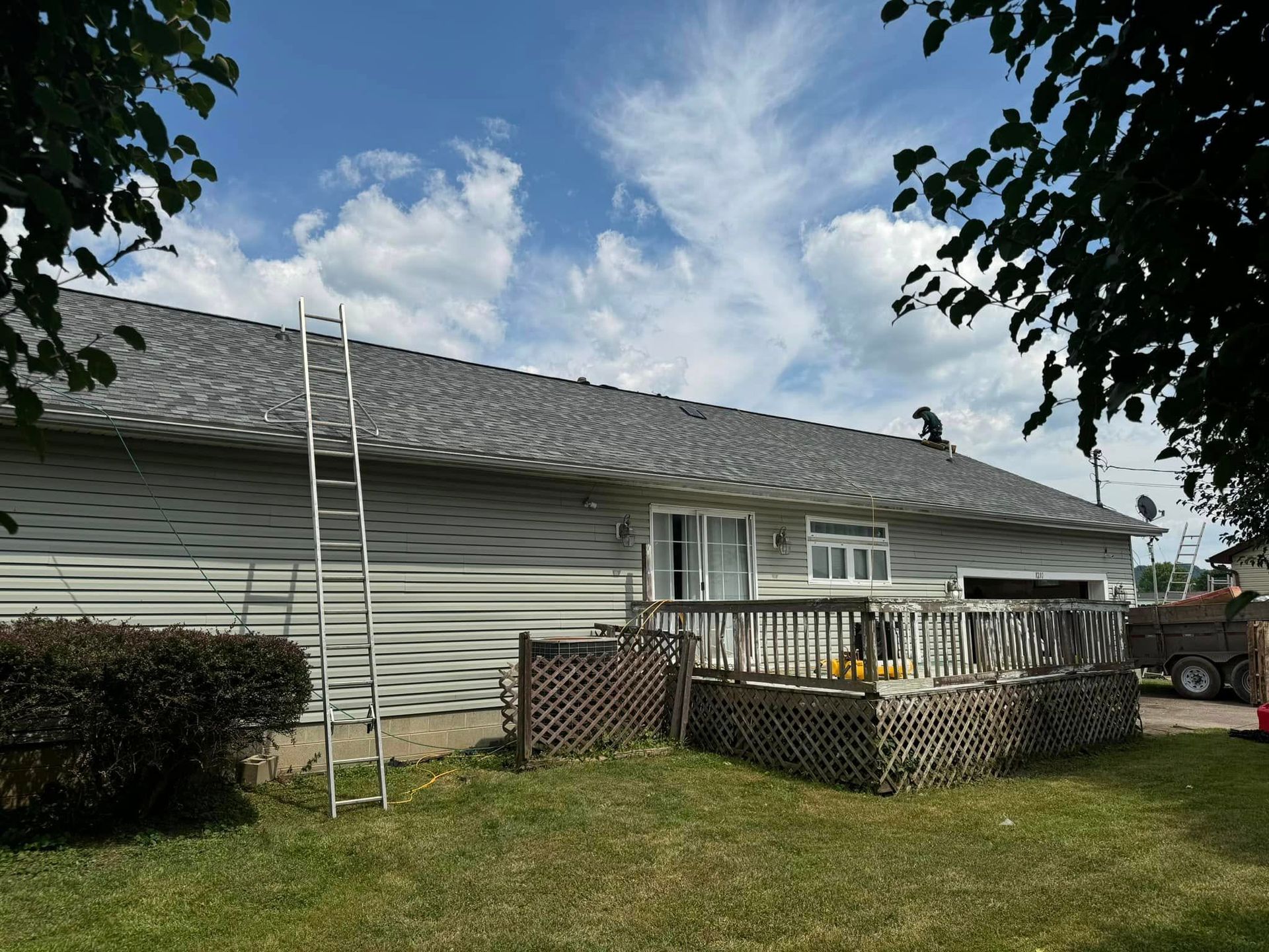 A house with a ladder on the roof and a deck.